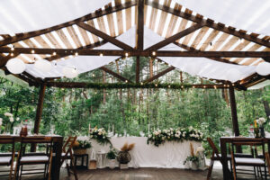 Bride and groom table decorated with flowers and lights in stylish boho wedding venue