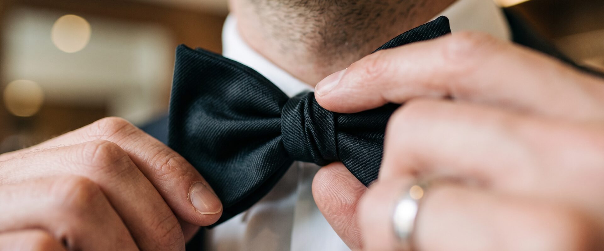 Man adjusting black bow tie in formal attire before an event