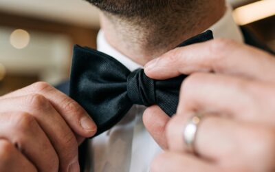 Man adjusting black bow tie in formal attire before an event
