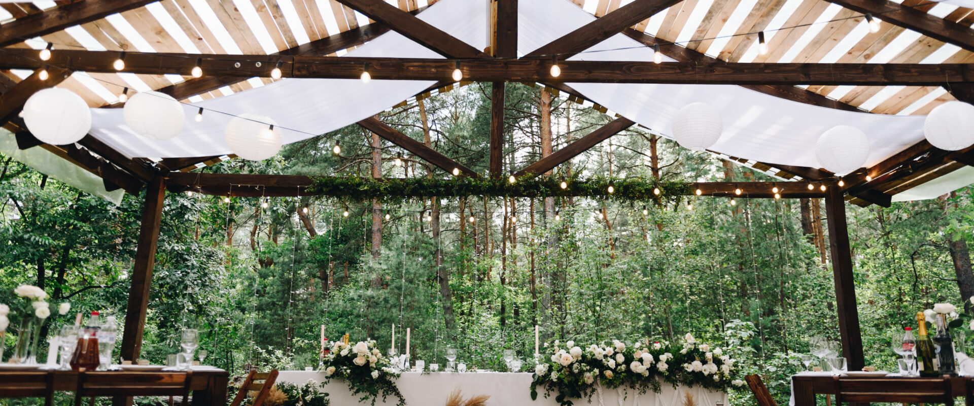 Bride and groom table decorated with flowers and lights in stylish boho wedding venue