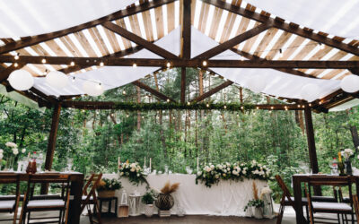 Bride and groom table decorated with flowers and lights in stylish boho wedding venue