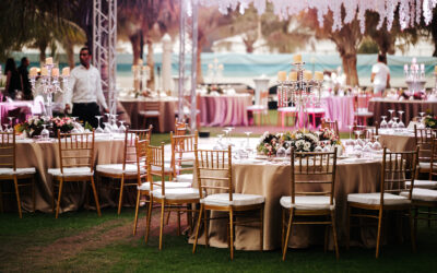 International Wedding outdoor celebration EVENING party under palm trees. Served tables on green area in hotel. Landyard. Beige and pink colors. Close-up and wide angle.